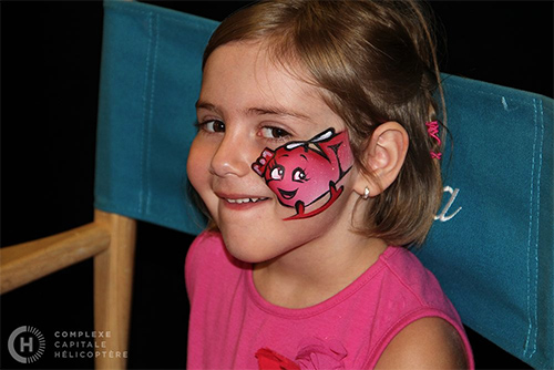 A child with helicopter face paint smiling at a World Helicopter Day event in Canada